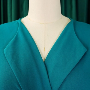 Détail du col en V élégant et de la texture du tissu vert paon sur cette robe chic