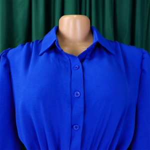 Detail of royal blue shirt collar with matching buttons and subtle puffed sleeves texture