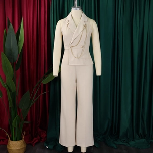 Detailed view of beige suit vest featuring double-breasted buttons and gold chain ornament