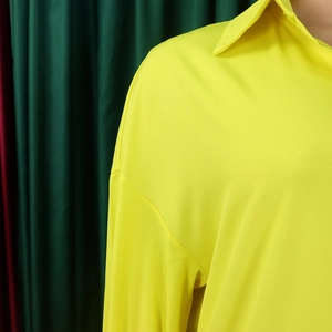 Close-up of the neon yellow lapel collar and shoulder stitching on a loose long-sleeved dress