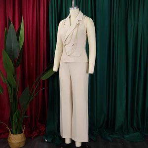 Detail of beige sleeveless blazer vest with metal chain and wide leg trousers