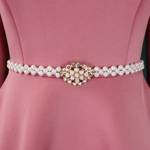 Detail of elegant pearl waist belt with gold floral rhinestone buckle on pink dress