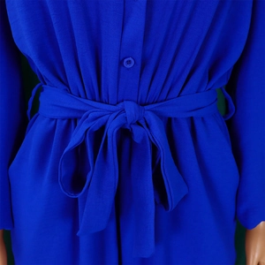 Detail of royal blue jumpsuit showing waist tie bow, button closure and textured fabric