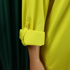 Detail of yellow long sleeve dress showing button tab sleeve and smooth fabric texture
