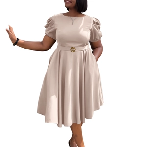 Détail d'une robe trapèze beige élégante avec manches bouffantes et boucle dorée