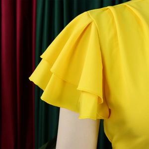 Détail d'un haut jaune avec des manches à volants étagées et texture d'épaule plissée