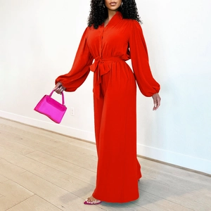 Detail view of orange long sleeve jumpsuit featuring waist belt and wide leg design