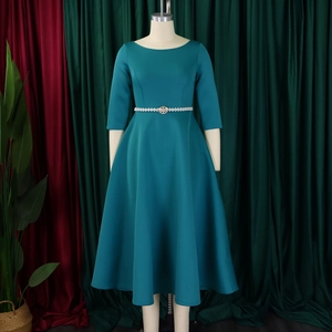 Detail of teal long-sleeve evening gown with a delicate pearl waist belt and flared hem