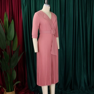 Détail d'une robe plissée rose à col en V avec ceinture et jupe mi-longue élégante