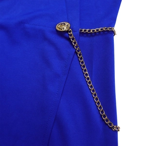 Detail of royal blue jumpsuit with golden lion embossed button and metal chain link