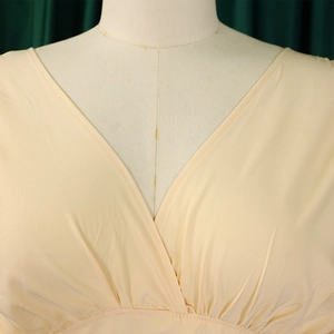 Détails d'une élégante combinaison abricot à col en V avec textures plissées à la taille