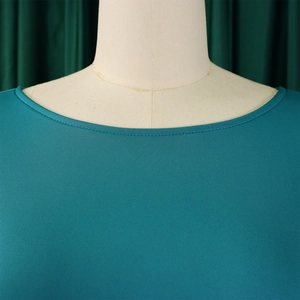 Close-up of teal knit dress neckline with detailed hemming and smooth fabric texture