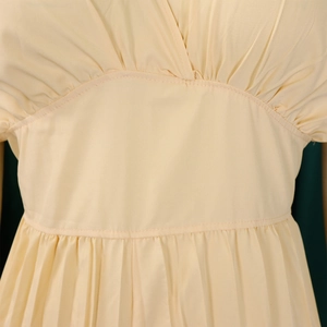 Détail de la taille haute plissée sur une combinaison de couleur jaune crème élégante