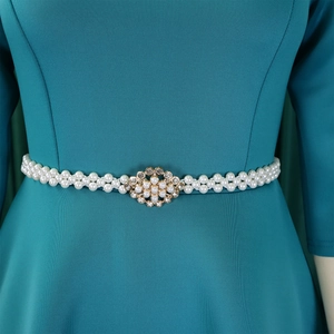 Close-up of elegant double-row pearl waist belt with gold floral rhinestone buckle