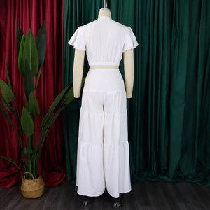Détail du crop top blanc en mousseline et du pantalon large à volants sur mannequin