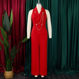 Detail of red sleeveless jumpsuit with blazer collar, double buttons and silver chain