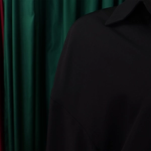 Detail of the shoulder and neckline on a black minimalist loose-fit long sleeve dress