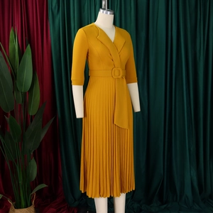 Détail d'une robe plissée jaune moutarde avec col en V et ceinture assortie à la taille