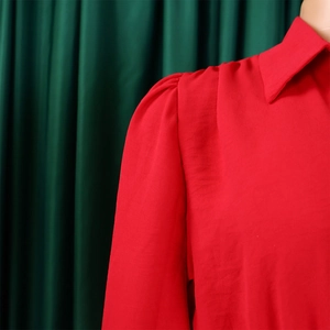 Detail of red long sleeve jumpsuit with puff shoulder and wrinkled chiffon texture