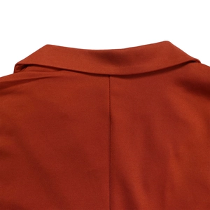 Detail eines hellorangen Blazers mit strukturiertem Revers und präziser Naht am Rückenteil