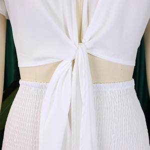 Détail du haut court blanc à nouer et du pantalon taille haute à taille froncée