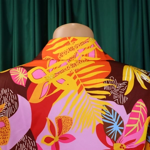 Détail de l'imprimé floral tropical sur chemise avec des feuilles de palmier orange et jaune