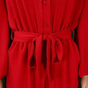 Detailed close-up of red long sleeve jumpsuit showing button closure and waist tie belt