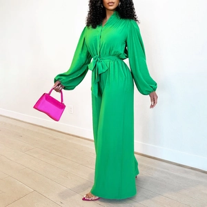 Detail of a bright green long sleeve jumpsuit featuring lantern sleeves and waist tie belt