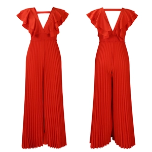 Détail d'une combinaison rouge avec col en V profond, manches à volants et pantalon plissé