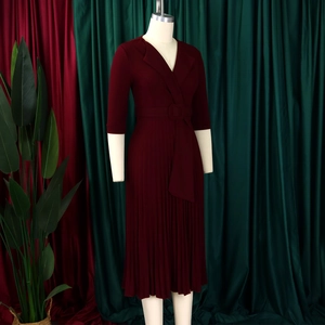Détail d'une robe plissée rouge foncé avec col en V, ceinture à la taille et boucle