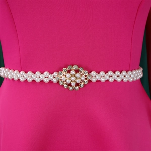 Detail of elegant pearl belt with gold floral buckle on a pink evening dress