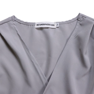 Détail du haut gris à col en V montrant la couture et la texture du tissu de l'ensemble