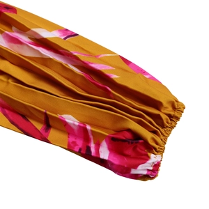 Dettaglio del polsino elastico a pieghe con stampa floreale rosa su abito lungo giallo