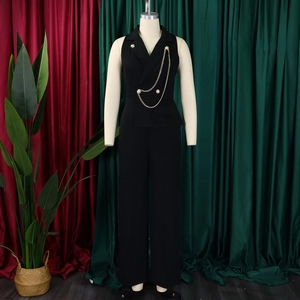 Detail of black sleeveless jumpsuit showing suit collar and decorative gold chains