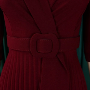 Détail de la robe plissée bordeaux avec décolleté en V et ceinture à boucle décorative