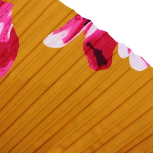 Dettaglio del tessuto plissettato effetto seta con stampa floreale su base giallo zenzero