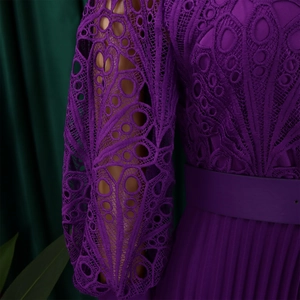 Detail of purple lace dress featuring intricate hollow-out embroidery and pleated skirt