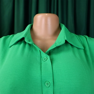 Detail of a bright green turn-down collar jumpsuit with matching buttons and twill fabric