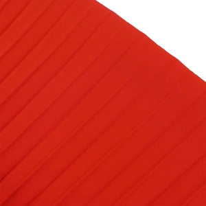 Détail du tissu plissé rouge avec de fines rayures accordéon et une texture soyeuse