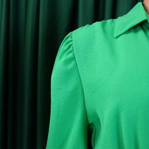 Detailed view of bright green crepe fabric textured blouse with elegant lapel collar