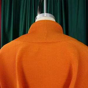 Dettaglio del top a pieghe arancione con trama fine e design a collo alto
