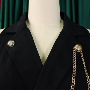 Detail of lapel collar with golden Medusa buttons and chunky chain on black jumpsuit