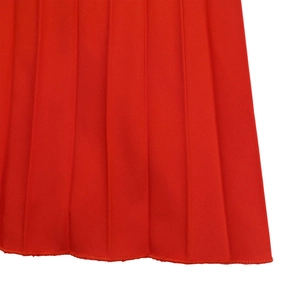 Détail macro du tissu plissé rouge vif avec des coutures fines et des plis verticaux