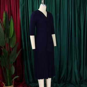 Détail d'une robe plissée bleu marine à col en V avec revers et ceinture assortie