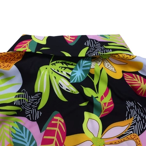 Détail du motif de feuilles tropicales sur chemise noire à revers avec fleurs colorées