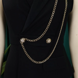 Detail of black vest with gold embossed buttons and layered metallic chain decoration