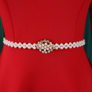 Detailed close-up of double-row pearl belt with floral rhinestone buckle on red dress