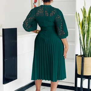Detail of dark green dress featuring intricate lace hollow-out back and pleated skirt texture