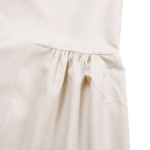 Detailed macro shot of fine pleats and texture on a cream asymmetrical midi dress