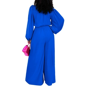 Back view of elegant royal blue long sleeve jumpsuit with loose wide leg trousers and pink bag